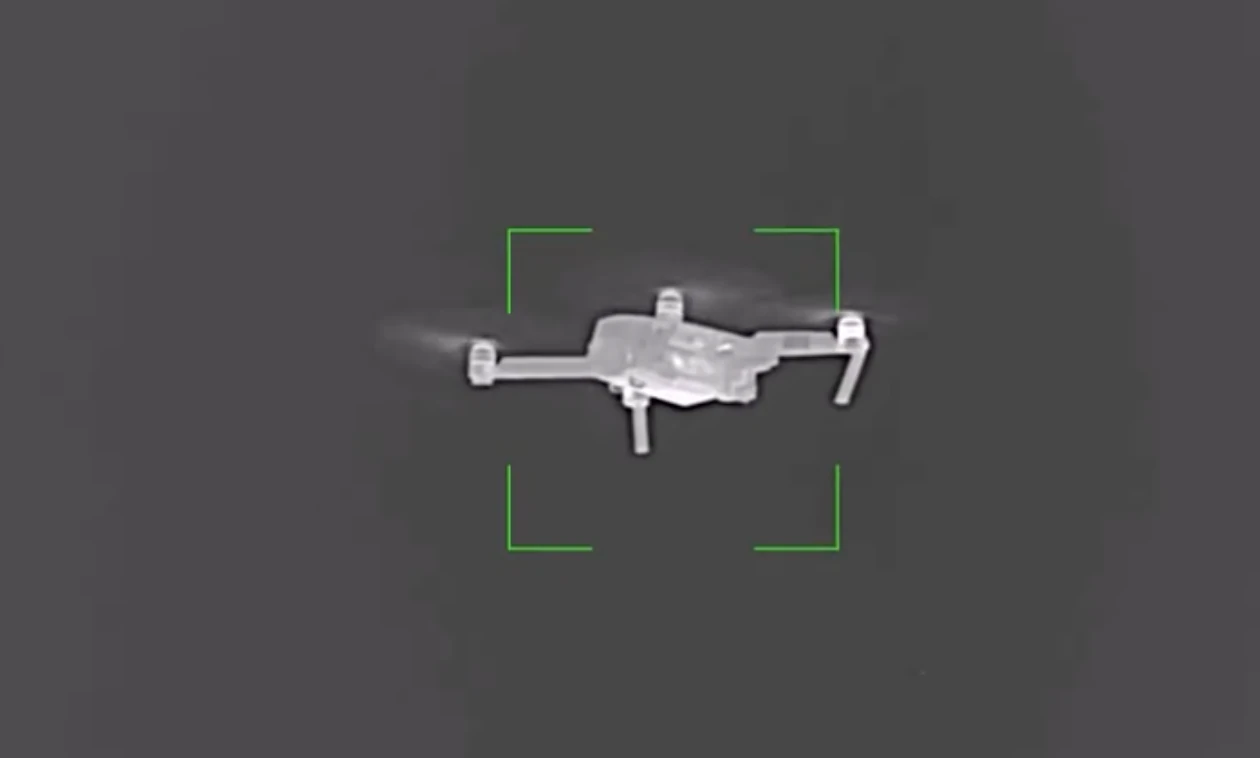 Thermal sensor view from a Gjall-equivalent interceptor: a small quadcopter framed inside a green tracking reticle, mid-flight against an open sky.